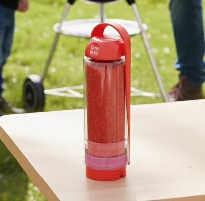 Red koor refillable bottle with a clear sleeve on a table outdoors
